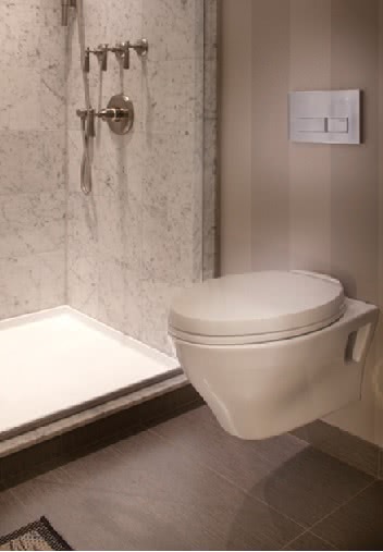 The Geberit system’s actuator panel and hardware are all that is visible, while the tank and flush valves are concealed behind the wall.